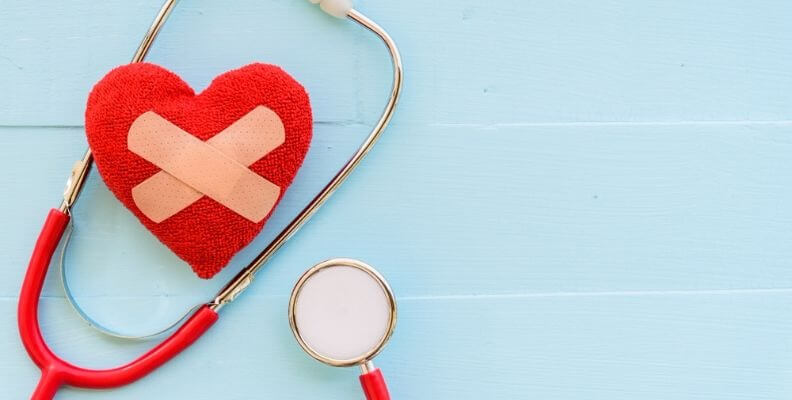 Stethoscope wrapped around a heart patch with bandages on it